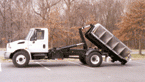 Hook lift’s dual pivot action dumps like a true dump truck