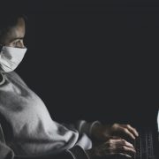 Woman typing on computer wearing a face mask